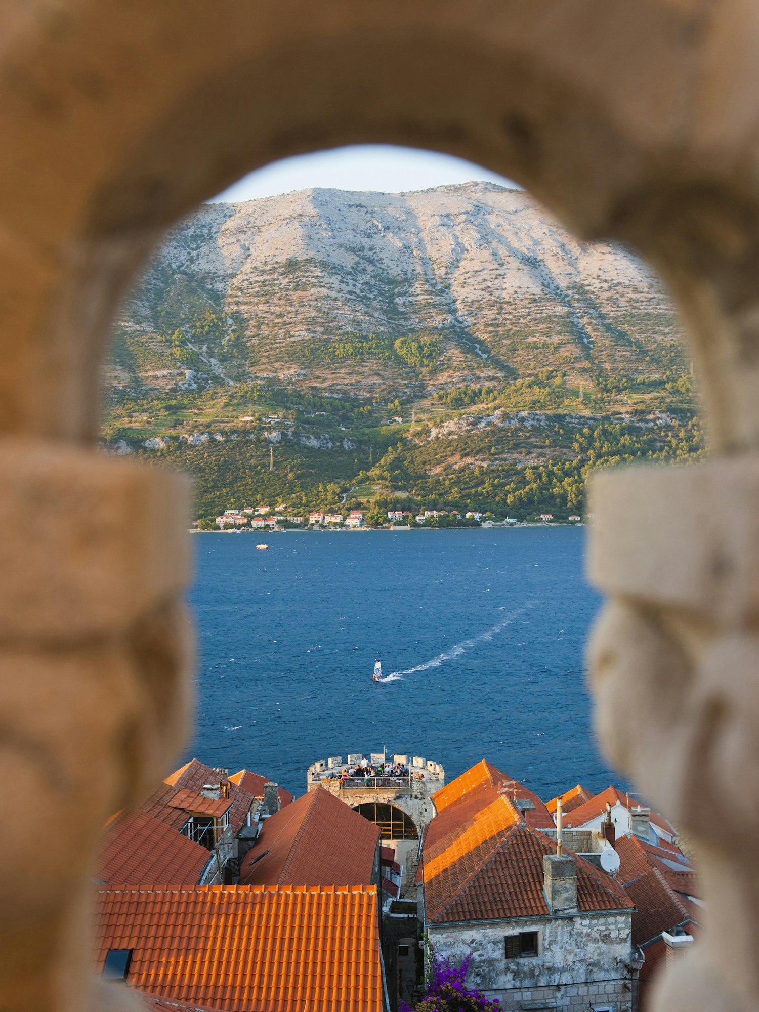 Windsurfer windsurfing at Korcula Town at sunset, seen from St Marks Cathedral bell tower, Korcula I